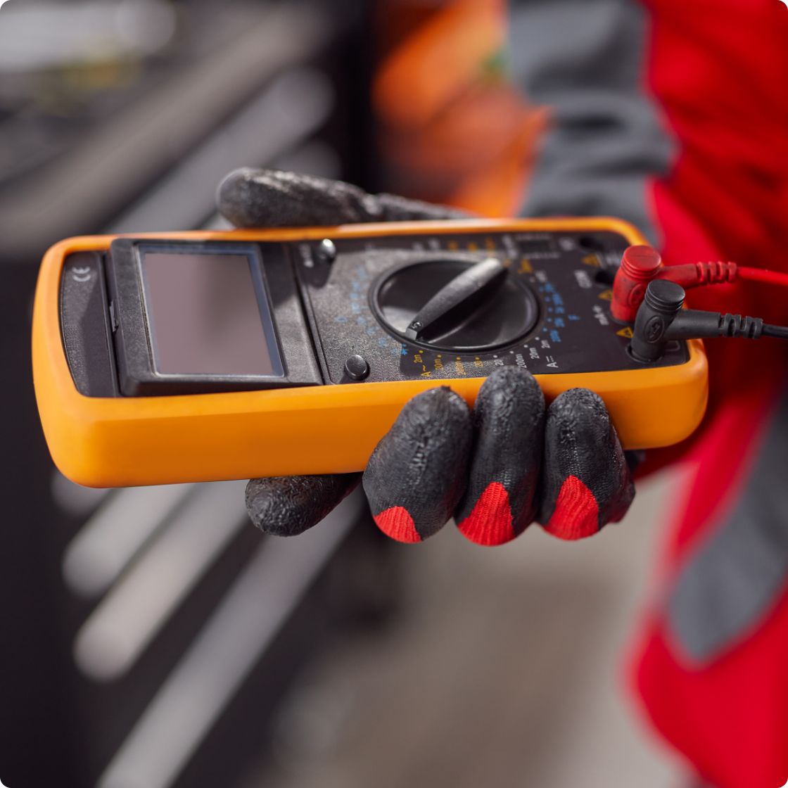 A multimeter in the worker's hand