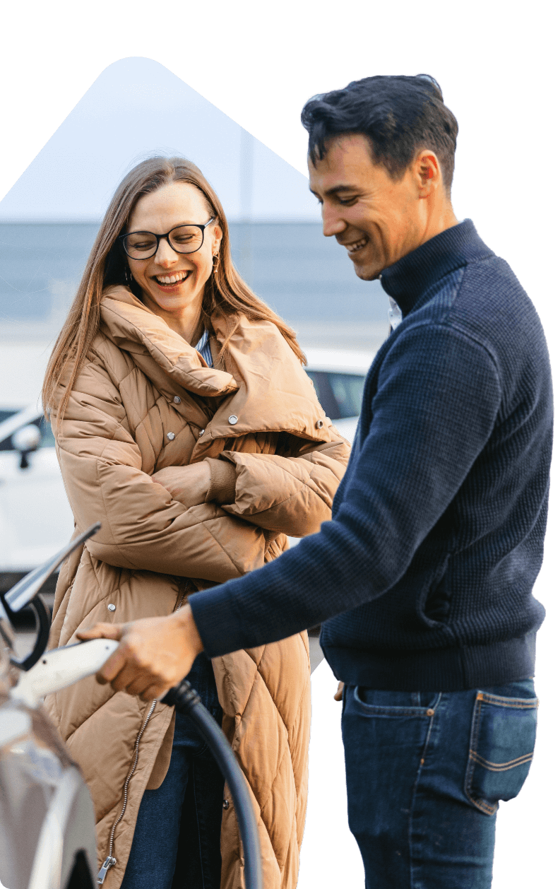 A smiling woman and man are charging an EV