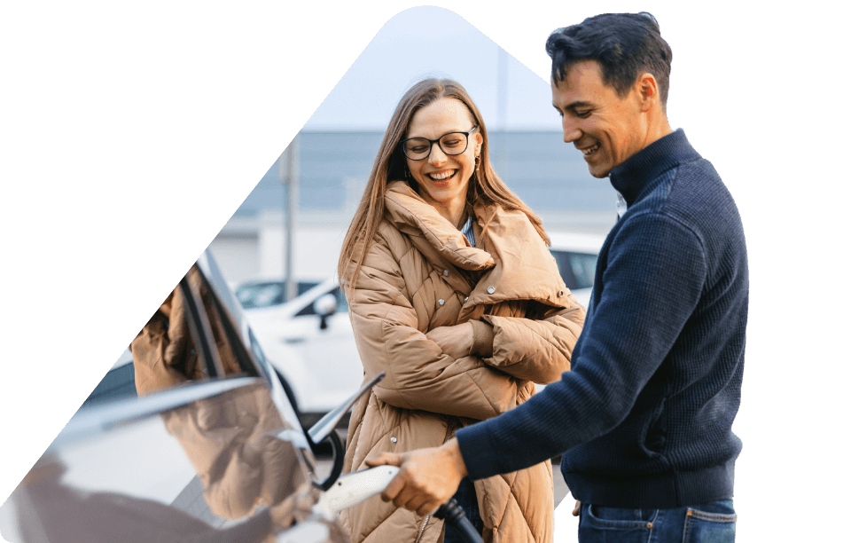 A smiling woman and man are charging an EV