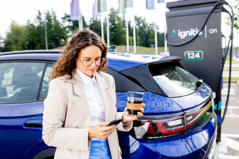 Sieviete uzlādē savu elektromobili