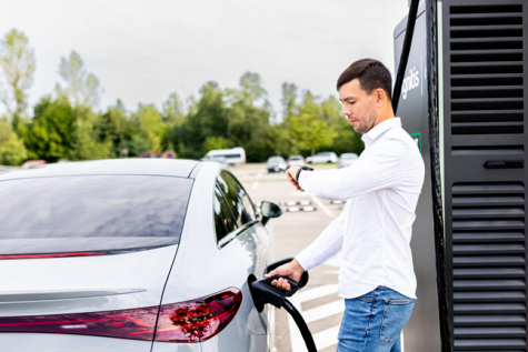 Vīrietis uzlādē savu elektromobili.