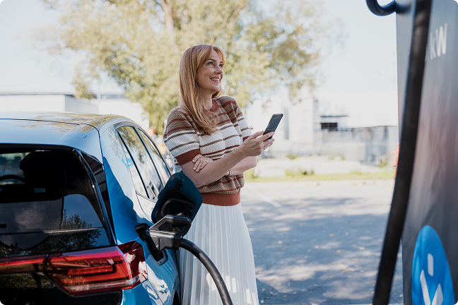 Sieviete uzlādē savu elektroauto.