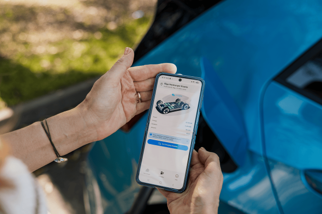 Sieviete rokā tur mobilo tālruni, kura ekrānā redzama Ignitis ON mobilā lietotne.