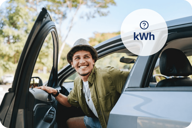 Vīrietis, izkāpjot no elektroauto, smaida, jo ir priecīgs uzzinājis, cik kWh nepieciešams, lai ar elektroauto nobrauktu 100 km.