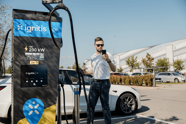 Vīrietis uzlādē savu elektroauto Ignitis ON ātrās uzlādes stacijā.