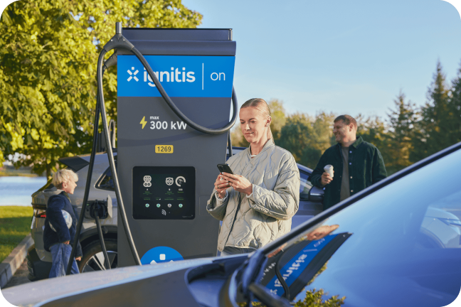 Sieviete kopā ar ģimeni uzlādē elektromobili Ignitis ON īpaši ātrās uzlādes stacijā.