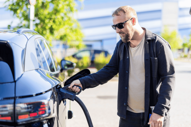 Vīrietis uzlādē savu elektroauto.